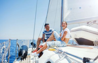 Familie lachend op het dek van een zeilboot tijdens een zomerdag op het water