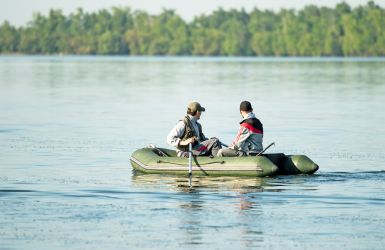 Twee mannen peddelen in een rubberboot over rustig water