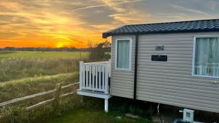 Stacaravan bij zonsondergang op een grasveld in natuurgebied