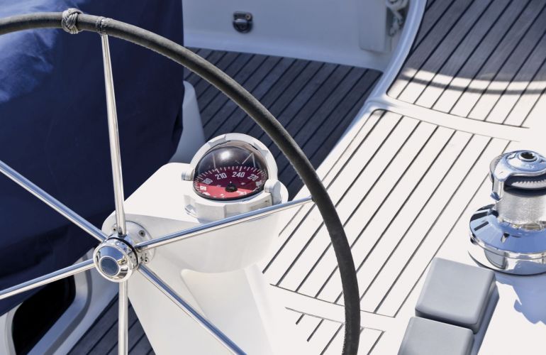 Close-up van een stuurwiel en kompas op het dek van een zeilboot