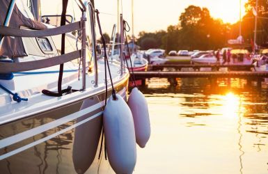 Zeilboot met stootwillen, bij ondergaande zon in de haven